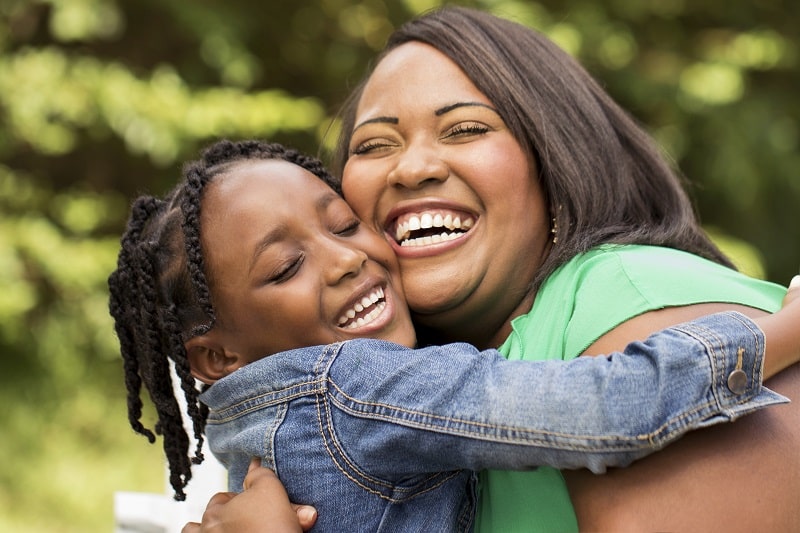 African American mother and daughter laughing and hugging each other.